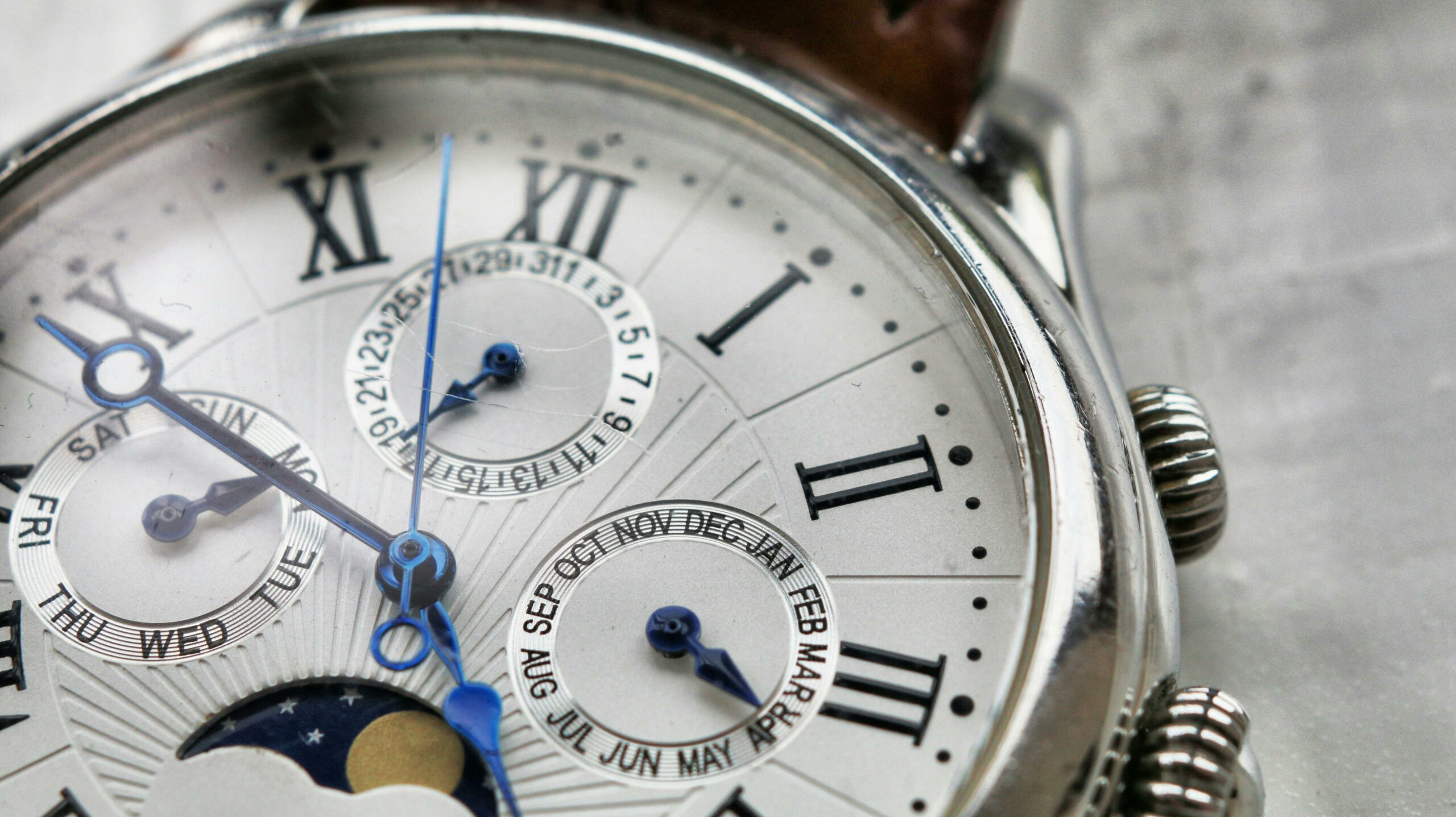 Detailed macro shot of an antique analog wristwatch with Roman numerals and calendar face.